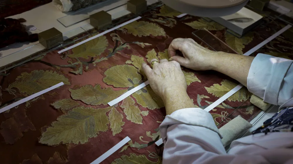 Gros plan sur des mains d'artisans sur une tapisserie